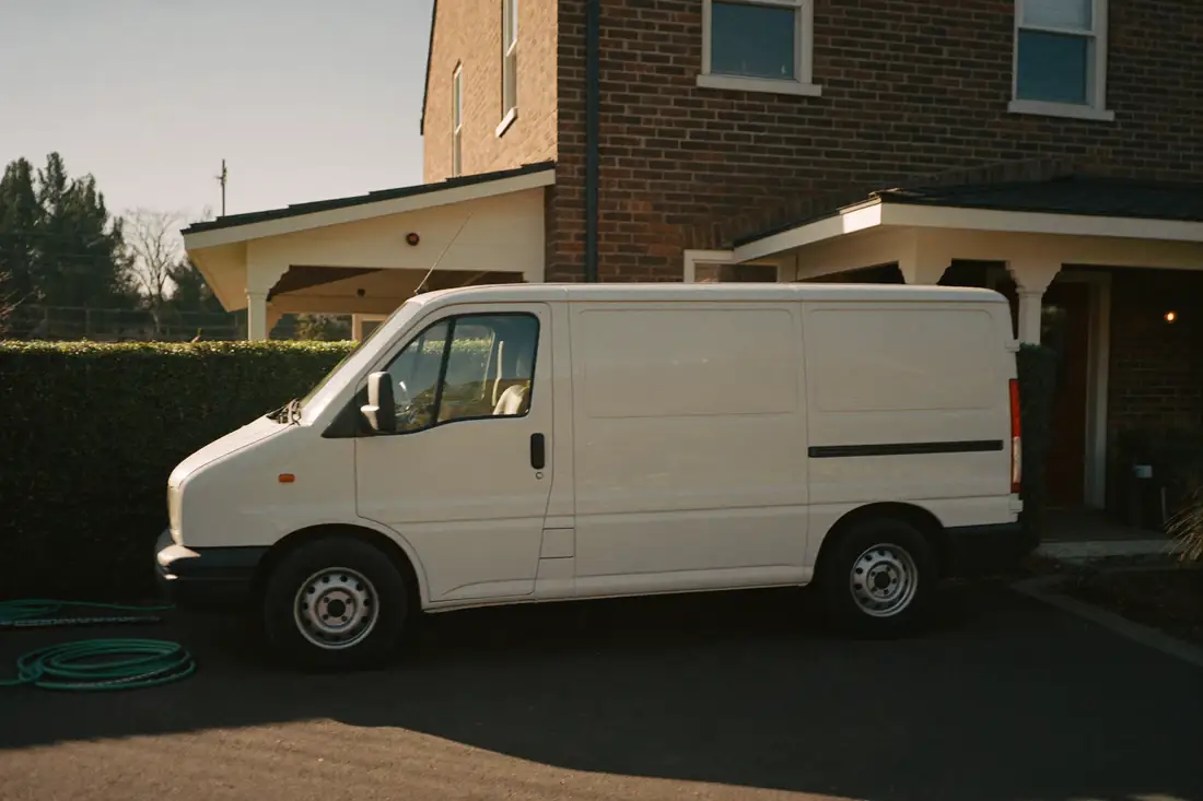 A clean white service van parked on a residential driveway in the morning